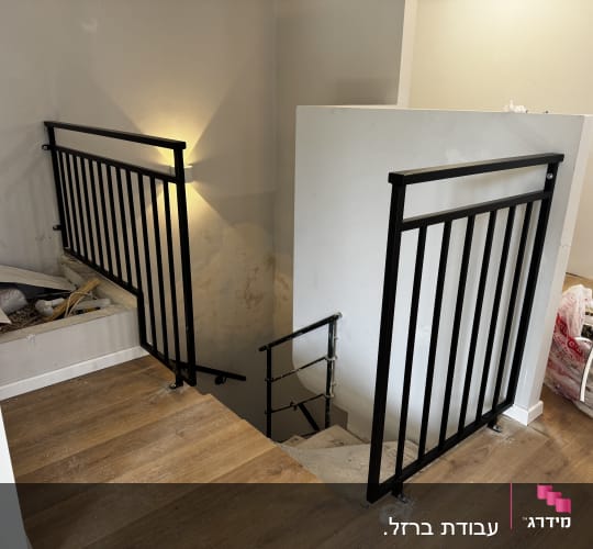 מעקה ברזל שחור על גרם מדרגות עץ